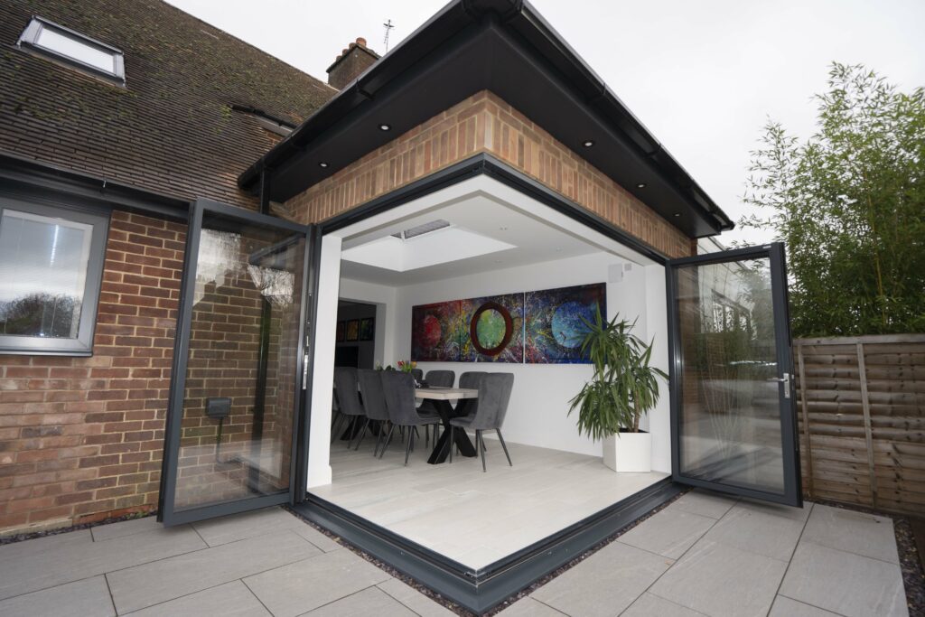 Aluminium bifold doors folded fully open across a contemporary extension