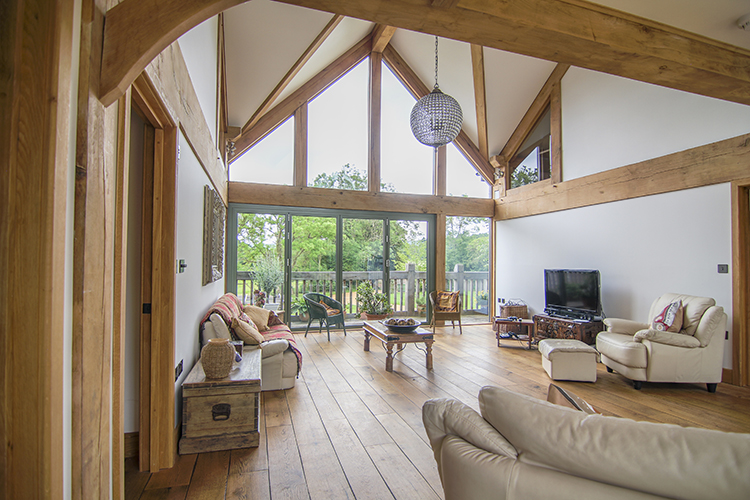 Oak-framed property with large fixed gable end windows above bi-fold doors